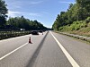 Sperrte Autobahn mit Leitkegel in der Mitte, Autos fahren auf der A7 zwischen Bäumen und Leitplanken vorbei.