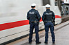 Zwei Beamte der Bundespolizei stehen am Bahnsteig neben einem vorbeifahrenden ICE.