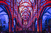 Rote und blaue Lichtbögen in einer Kirche mit Gewölben und Säulen
