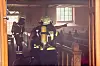Feuerwehrleute sichern einen verrauchten Kirchenraum zwischen Holzbänken und Altarbereich.