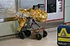 Mit goldener Folie umwickelter Kinderwagen in einem Innenraum neben Glas und Metall.
