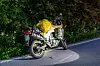 Beladenes Motorrad am Straßenrand neben dichter Vegetation auf einer kurvigen Landstraße.
