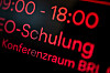 Leuchtende Anzeige mit „E-Schulung“ und „Konferenzraum BRI“ in roter Schrift auf dunklem Hintergrund.