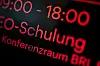Leuchtende Anzeige mit „E-Schulung“ und „Konferenzraum BRI“ in roter Schrift auf dunklem Hintergrund.