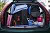 Vollgepackter Kofferraum mit Taschen, Decken, Kühlbox und Ball als Beispiel für Autoüberladung.