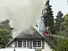 Feuerwehr löscht Dachstuhlbrand in Hamburg, dichter Rauch steigt über Einfamilienhaus auf.