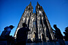 Touristen fotografieren den Kölner Dom vor blauem Himmel