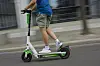 Mann fährt auf Lime-E-Scooter auf einer Straße in Berlin.