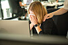Frau am Schreibtisch mit bedecktem Gesicht, eine Hand liegt tröstend auf ihrer Schulter im Büro.