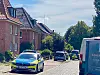 Polizeiwagen mit blau-gelber Lackierung in einer Wohnstraße vor Backsteinhäusern.