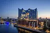 Elbphilharmonie bei Sonnenaufgang mit Spiegelungen in der Glasfassade an der Elbe in Hamburg.