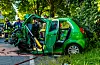 Einsatzkräfte sichern einen stark beschädigten grünen Kleinwagen am Straßenrand nach einem Unfall.