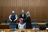Angeklagter hält Mappe vor das Gesicht, neben ihm Justizbeamter und zwei Verteidiger im Gerichtssaal.