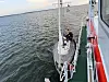 Segelboot auf ruhiger See mit mehreren Personen an Deck bei Arbeiten an Mast und Leinen.