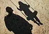 Schatten eines Erwachsenen und eines Kindes auf hellem Pflaster.