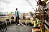 Person auf Dachterrasse zwischen Pflanzen, blickt über die Stadt nach einem Todesfall.