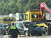 Polizisten an einer Unfallstelle mit beschädigten Fahrzeugen und Abschleppfahrzeug auf einer Straße.