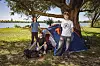 Joris, Johannes und Lennardt stehen und sitzen vor einem Zelt am Elbufer auf dem Campingplatz Lühesand.