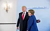 Merkel begrüßt Trump im Hotel Atlantic vor blauem Hamburg-Hintergrund.