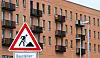 Mehrfamilienhäuser in Kronsrode hinter einem Baustellenschild im Neubaugebiet Hannover.