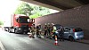 Feuerwehrleute sichern Unfallstelle unter einer Brücke neben Auto und Lastwagen.