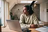Mann mit Headset arbeitet in Berlin am Esstisch mit Laptop und Aktenordner.