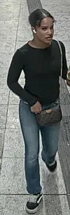 Person in schwarzem Oberteil und Jeans geht durch einen hellen, gefliesten Innenbereich.