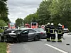 Beschädigtes Auto nach Unfall, Feuerwehrkräfte sichern die Straße ab.
