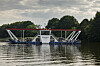 Fähre «Missunde III» mit Autos auf der Schlei vor bewaldetem Ufer.