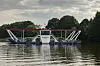 Fähre «Missunde III» mit Autos auf der Schlei vor bewaldetem Ufer.