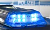 Blau blinkendes Blaulicht auf einem Polizeifahrzeug vor unscharfem Polizeihintergrund.