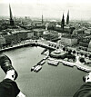 Jungfernstieg und Hamburger Rathaus von oben, Binnenalster mit Booten, Beine eines Fotografen im Vordergrund.