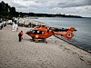Rettungshubschrauber Christoph 12 landet am Strand, Helfer stehen daneben.