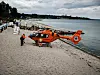Rettungshubschrauber Christoph 12 landet am Strand, Helfer stehen daneben.