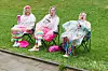 Teilnehmer des Schlagermove in Hamburg sitzen mit Regenschirmen und Regenponchos auf der Helgoländer Allee.
