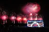 Menschen schauen am National Mall in Washington ein großes Feuerwerk über einer beleuchteten Bühne.