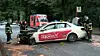 Einsatzkräfte sichern eine Unfallstelle mit zwei stark beschädigten Autos an einer Waldstraße.