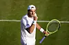 Jan-Lennard Struff im weißen Tennisoutfit mit Schläger auf dem Rasen von Wimbledon.