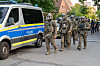 SEK-Beamte in Schutzkleidung gehen neben einem Polizeiwagen in einer abgesperrten Straße in Hamburg-Billstedt.