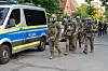 SEK-Beamte in Schutzkleidung gehen neben einem Polizeiwagen in einer abgesperrten Straße in Hamburg-Billstedt.