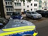 Polizeiwagen vor Wohnhaus in Hamburg-Eißendorf; im Hintergrund stehen Anwohner und mehrere Autos.