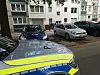 Polizeiwagen vor Wohnhaus in Hamburg-Eißendorf; im Hintergrund stehen Anwohner und mehrere Autos.