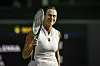 Aryna Sabalenka steht auf dem Wimbledon-Court und hält ihren Tennisschläger hoch.