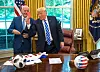 Trump hält im Oval Office eine rote Karte hoch, Infantino steht daneben.