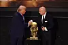 Donald Trump und Gianni Infantino stehen neben einer goldenen FIFA-Trophäe und begrüßen sich.