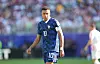 Kylian Mbappé im blauen Frankreich-Trikot auf dem Spielfeld, im Hintergrund verschwommene Zuschauer.