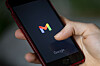 Hand hält Smartphone mit Gmail-Logo auf dem Bildschirm.