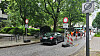 Autos warten an einer Baustelle auf einer von Bäumen gesäumten Straße.