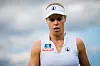 Laura Siegemund im weißen Wimbledon-Outfit mit Schirmmütze auf dem Platz, fokussierter Blick.