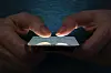 Hände tippen auf ein Apple iPhone 13 in dunkler Umgebung.
